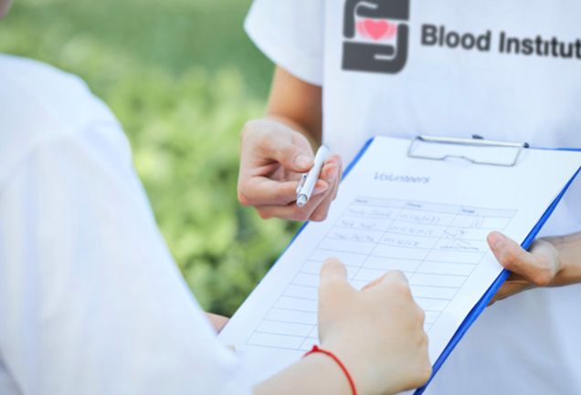 An Our Blood Institute volunteer asks for sign-ups